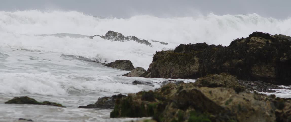Large waves are crashing into rocks and water is flowing