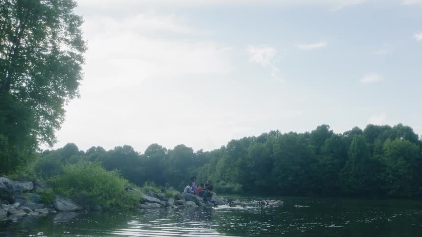 A family sits on a rural lakeshore