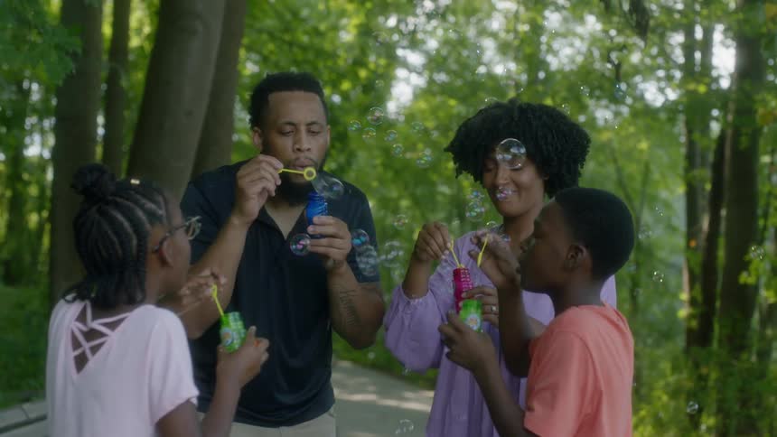 Family of four blows bubbles in the woods
