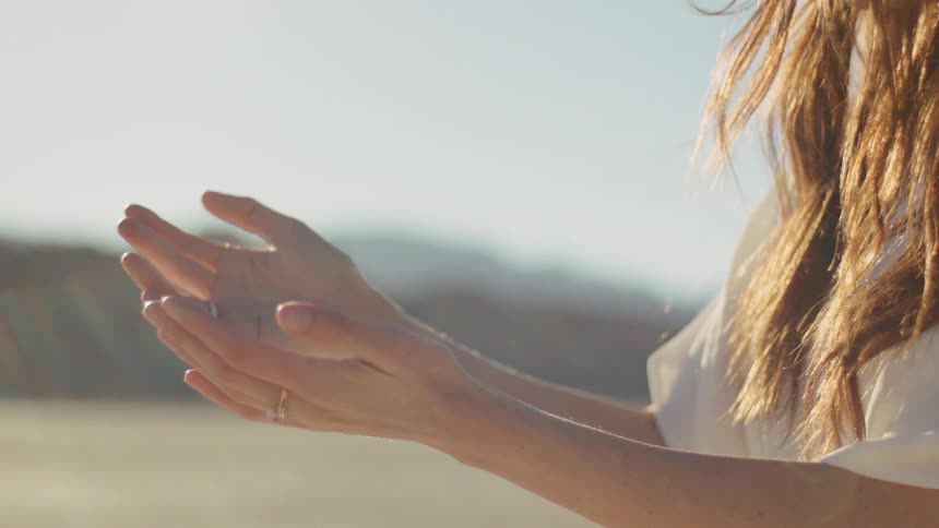 A woman cupping her hands and raising one into the air