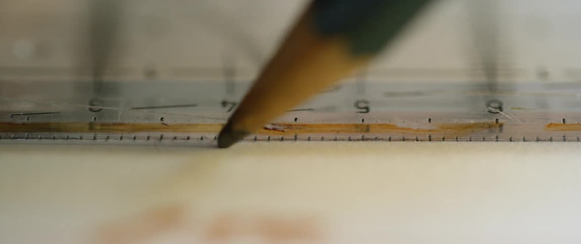 Person draws a line against a ruler with a pencil