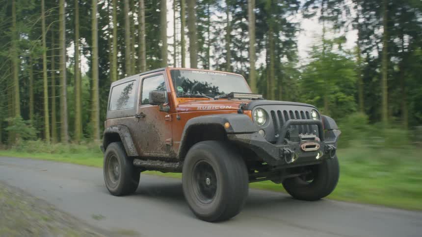 Jeep drives down a country road surrounded by trees