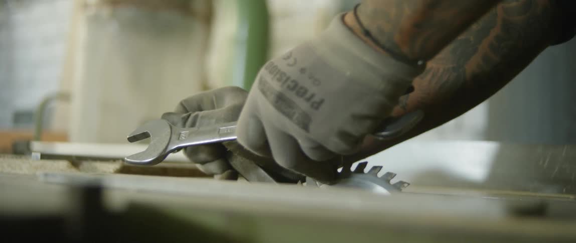 A man adjusting a table saw with tools