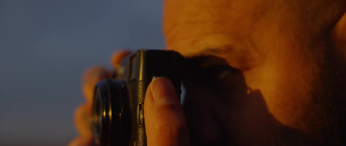 A man takes a photograph at sunset