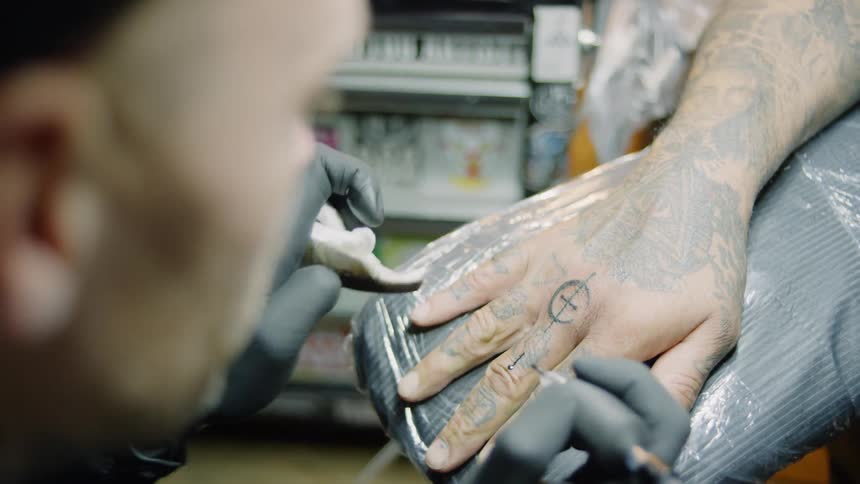 A man tattoos a customer's hand