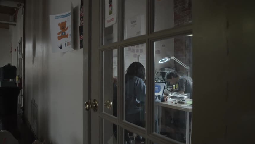 View through a door window of a couple sitting at a desk working