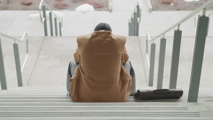 A man is sitting on the steps with his briefcase