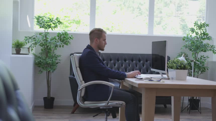 Man in office sits at desk and types on computer keyboard