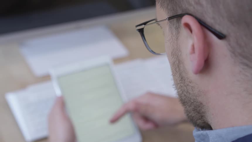 A man is using his tablet at a desk