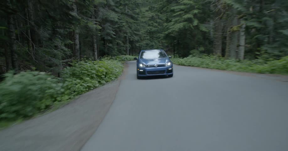 A blue volkswagen travels in a forest