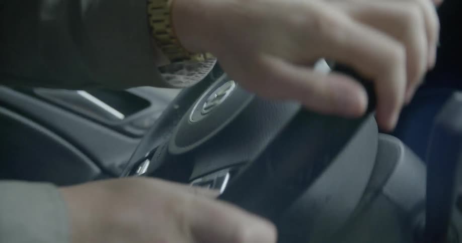 Man with a large gold watch driving fast and spinning the wheel quickly