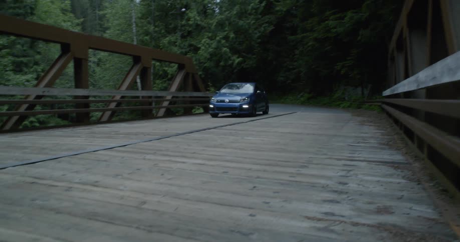 A vehicle drives over the wooden bridge
