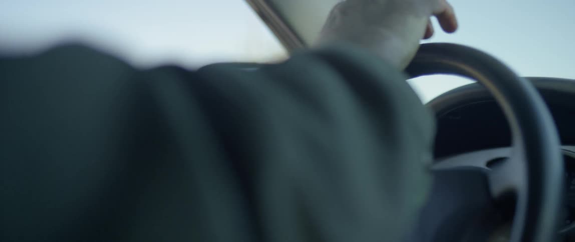 A closeup of a person's hands turning the steering wheel inside a vehicle
