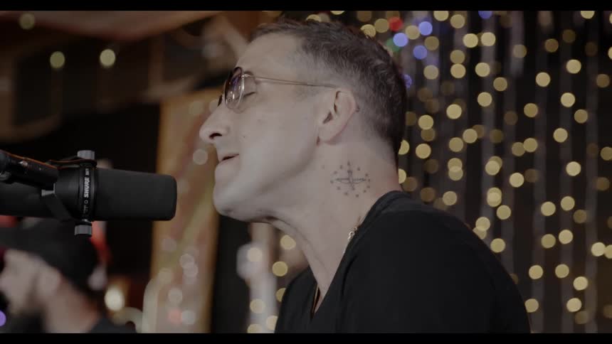 A musician sings into a microphone while playing with a band