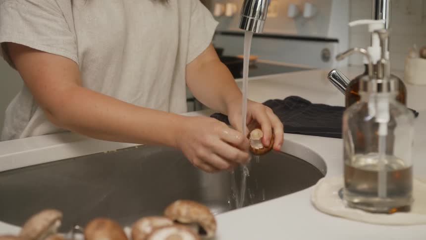 Woman washes mushrooms off in the sink