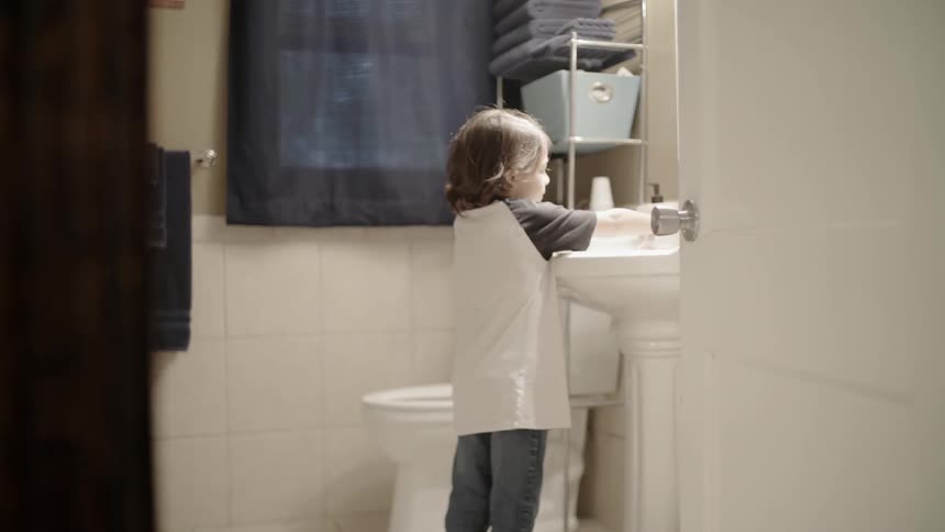A young boy washes his hands in a bathroom