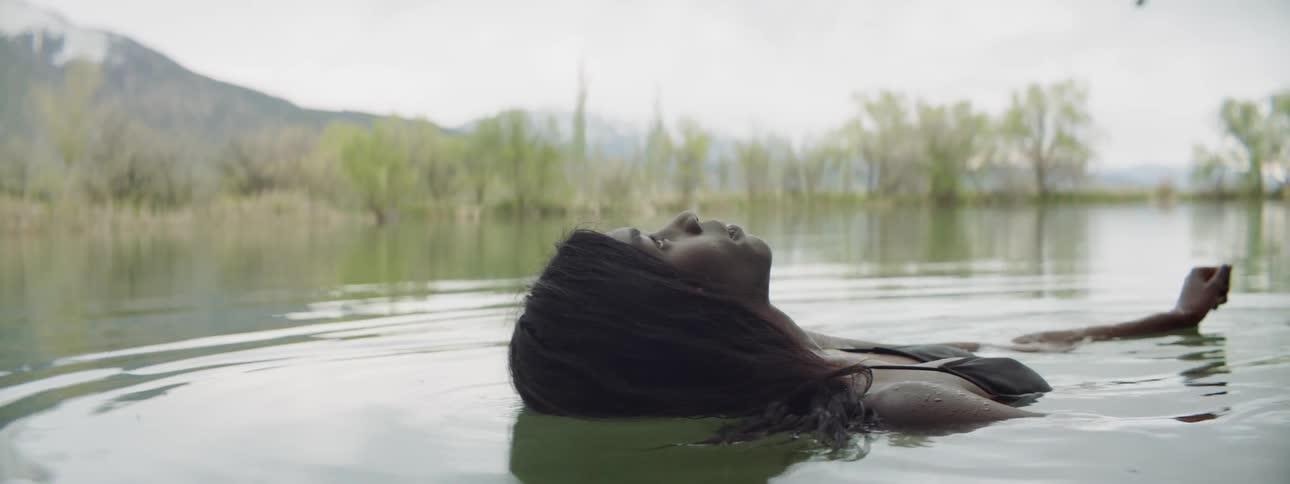 A woman lies back in water while swimming in a lake