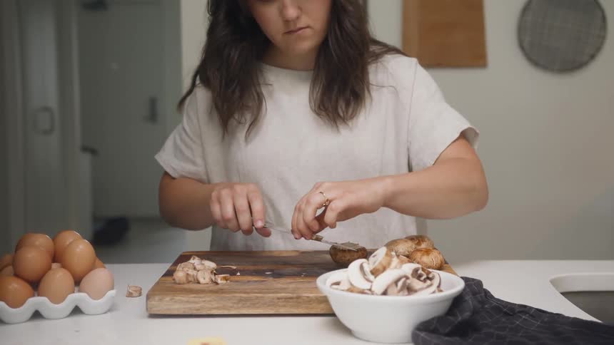 A woman is cutting mushrooms on the table