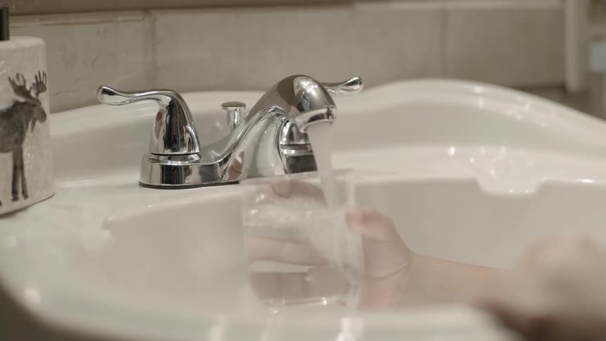 A child fills a glass with water