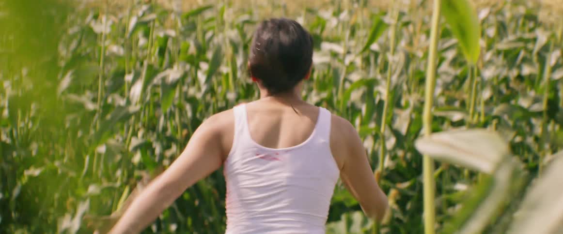 A scared and bloody woman fleeing through a field