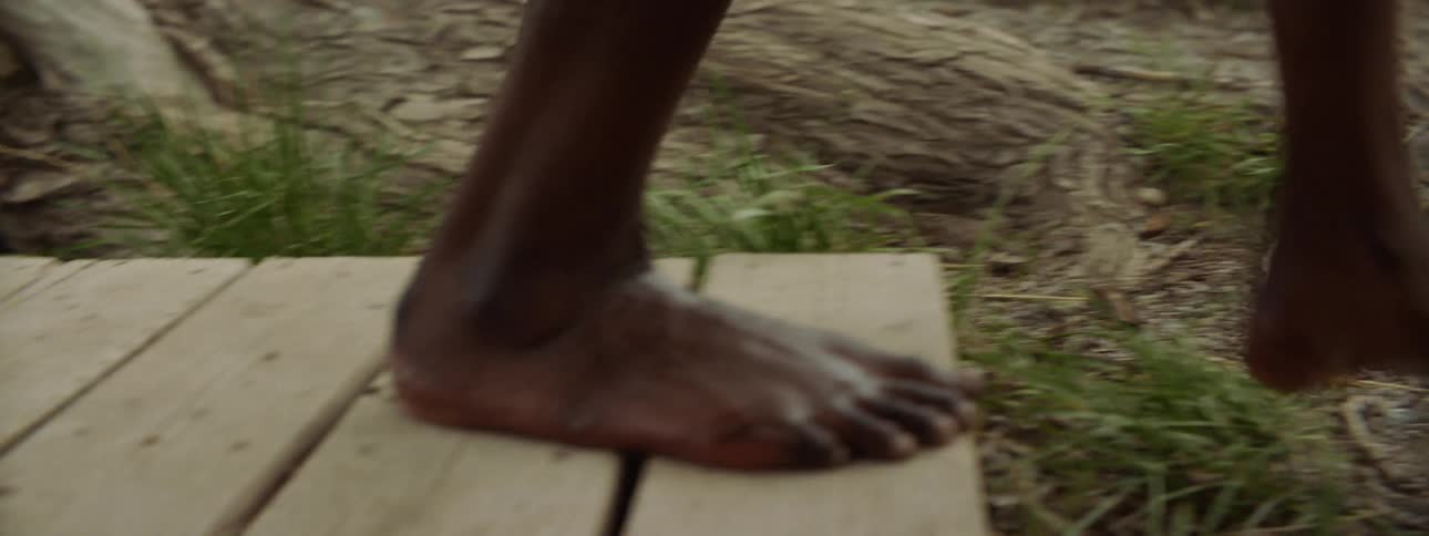 A person gets out of the lake water and walks on the field