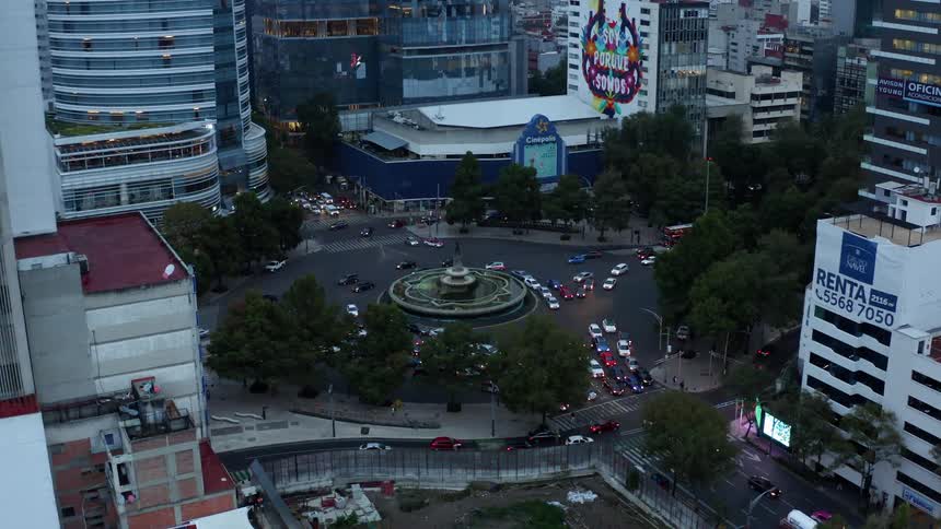 Cars drive on a city street near skyscrapers