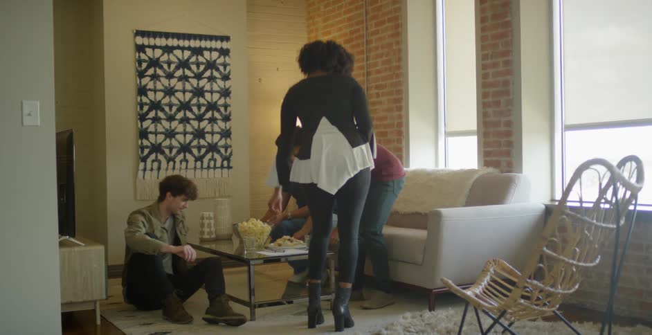 A few friends walk in to the living room to share food and talk