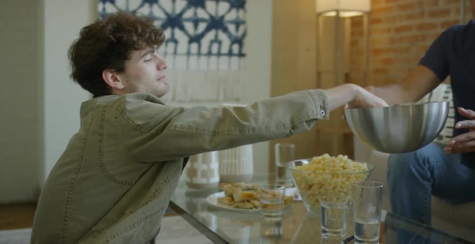 A man writes on a slip of paper and tosses it into a bowl before picking out another slip