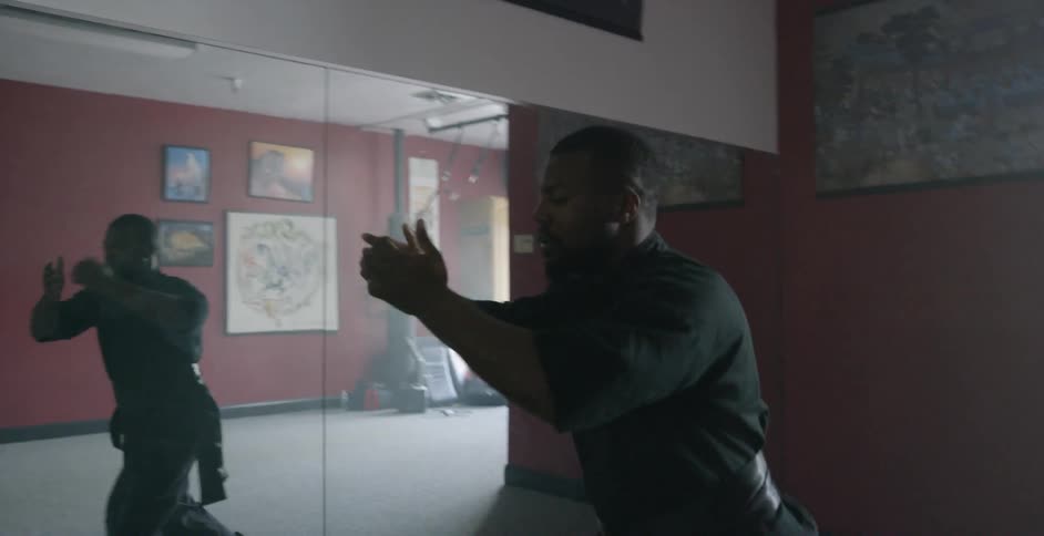 A man practices martial arts forms and moves in a mirrored studio