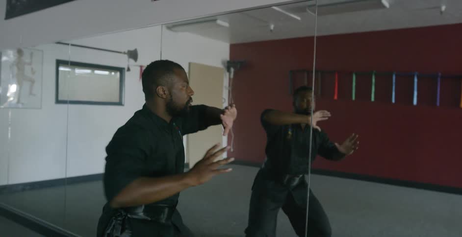 Man practices martial arts in front of mirror