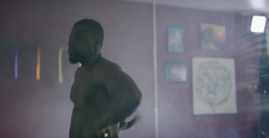 Man practices nunchuck moves in a dark gym while standing in front of a mirror