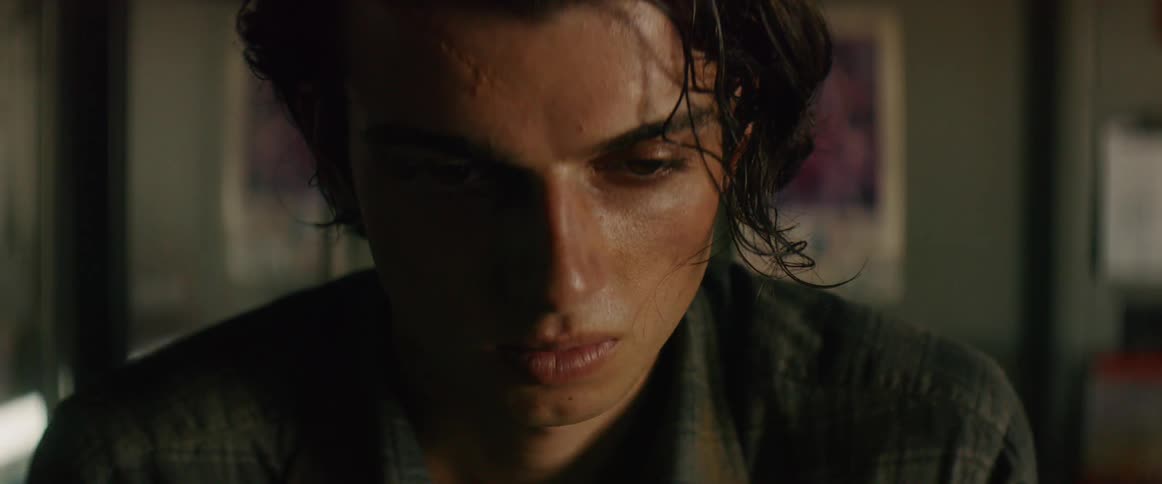 A young man with greasy hair frowns and closes his eyes
