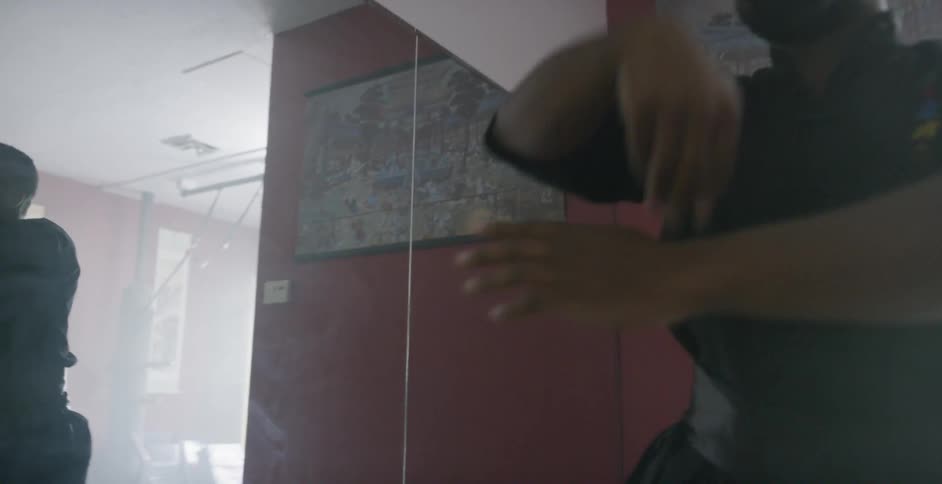 A man does martial arts exercises in front of a mirror
