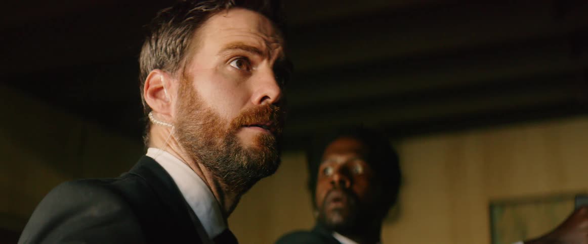 Two men wearing suits with ear pieces startled by flashing lights
