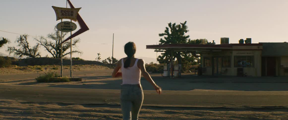 A woman runs towards a rural motel