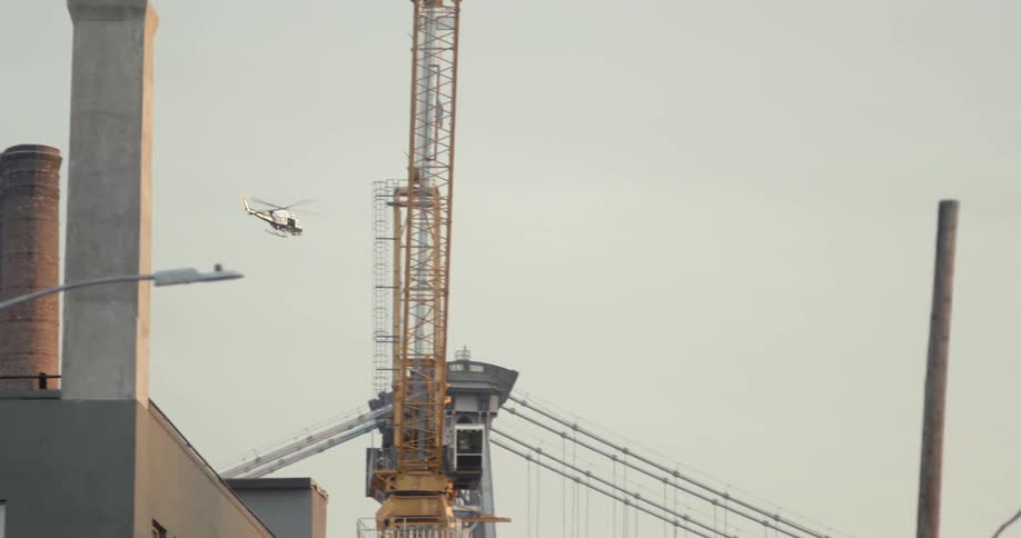 A helicopter in the sky flying over a factory area