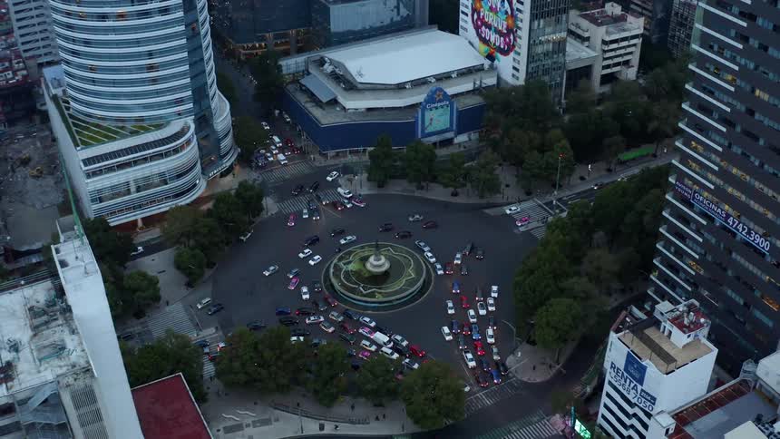 The vehicles drive together around the circle in the city