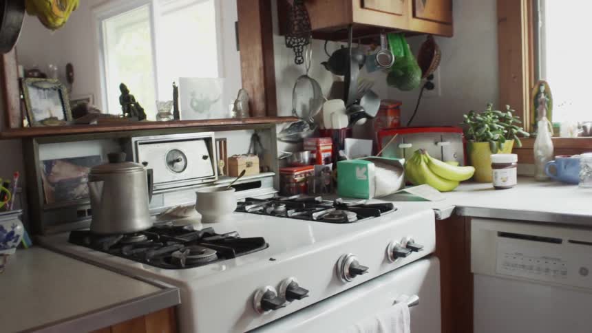 A white stove in a cluttered but neat kitchen