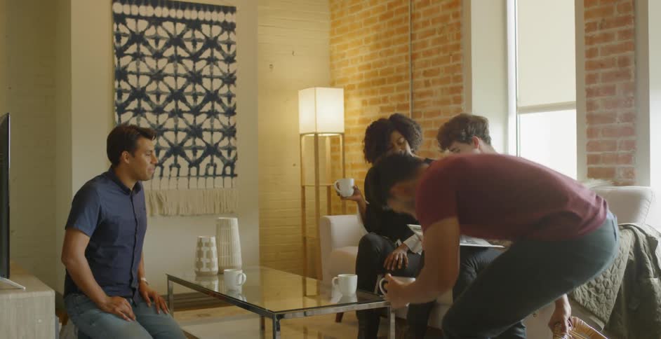 A group of friends hanging out and looking at a book together