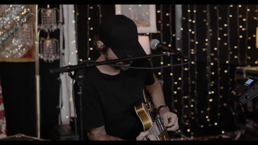 A man plays guitar in front of a mic on a stand