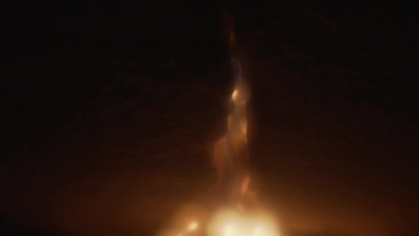 Fire trailing down a split rock wall into darkness