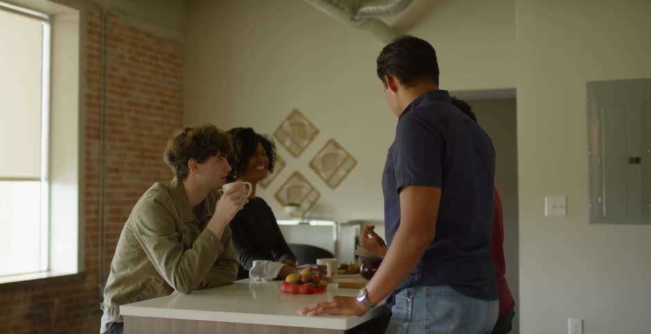 People standing and sitting in the kitchen talking