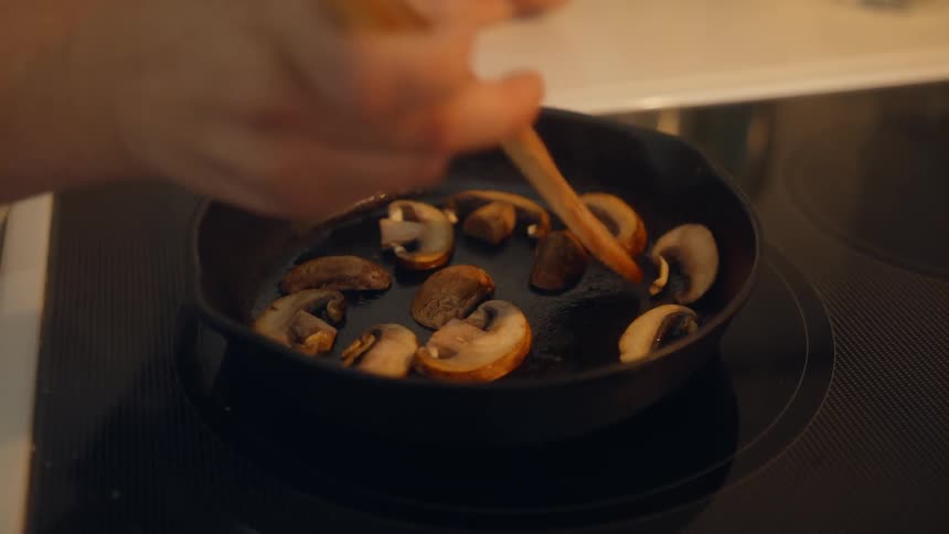 Woman cooks mushroom in nonstick pan in the kitchen