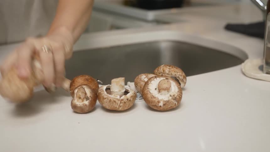 A woman taking mushrooms out of a bag and placing it near a sink