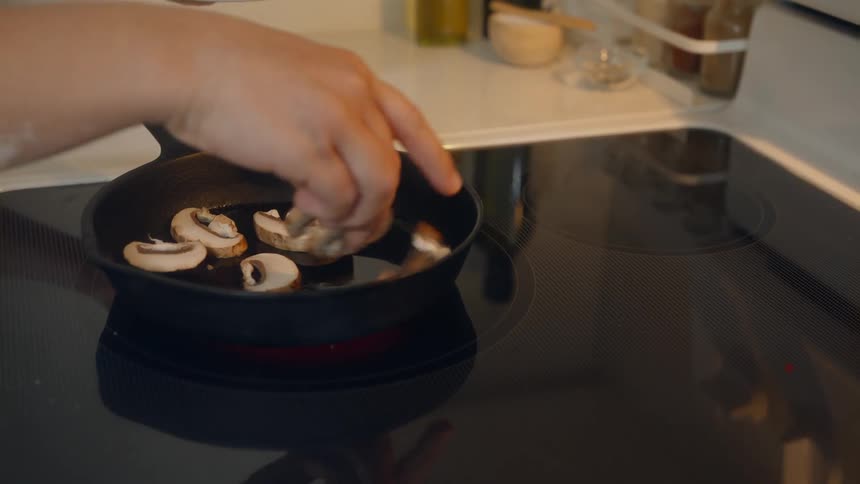 Person pours oil in a cast iron skillet and puts mushrooms in