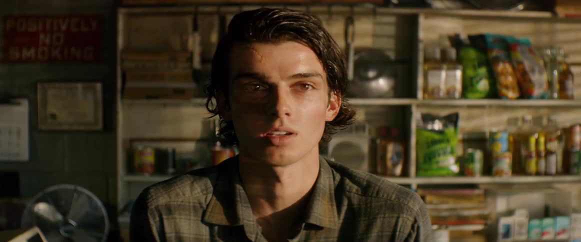 A young man with brown hair talks to two people