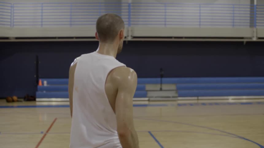 A sweaty man walks through a gymnasium