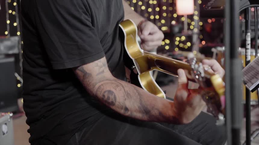 A man sitting in a studio playing the guitar