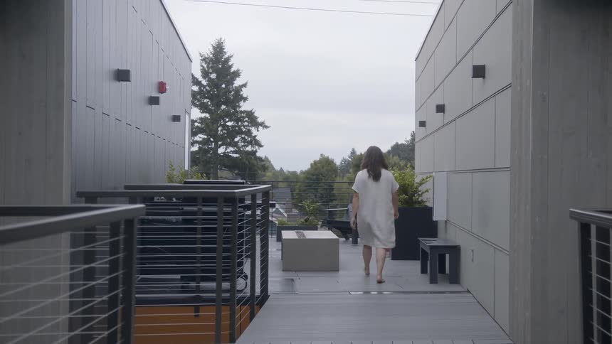 Woman carrying scissors and walking across a patio barefoot
