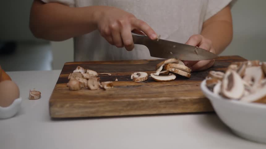 A man slices mushrooms on a wooden cutting board
